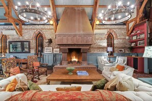 A spacious living room with a fireplace, wooden beams, and a chandelier. - Incredible Coastal Castle on Sullivans Island (Sullivans Island)