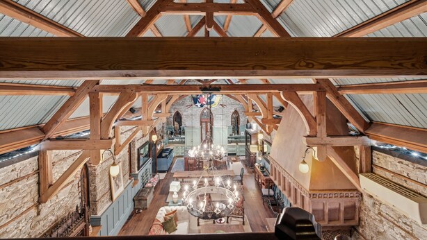 An interior with a high ceiling, wooden beams, stone walls, and a central chandelier. - Incredible Coastal Castle on Sullivans Island (Sullivans Island)
