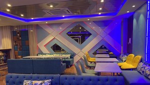 A modern lounge area with blue and yellow seating, a central table, and geometric wall designs. - Hotel Brij Residency (Bhopal)