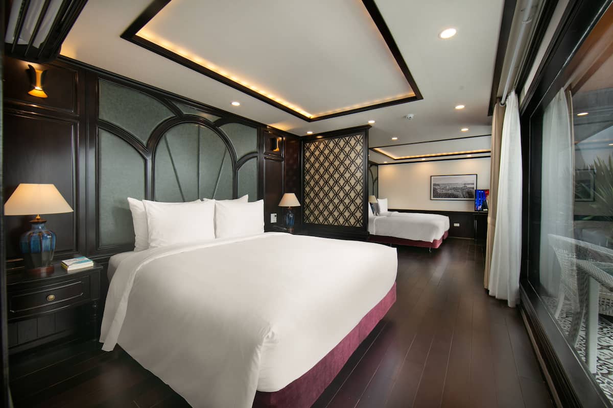 Habitación de hotel con una cama grande, mesitas de noche con lámparas, un papel tapiz con diseño y vistas por la ventana.
