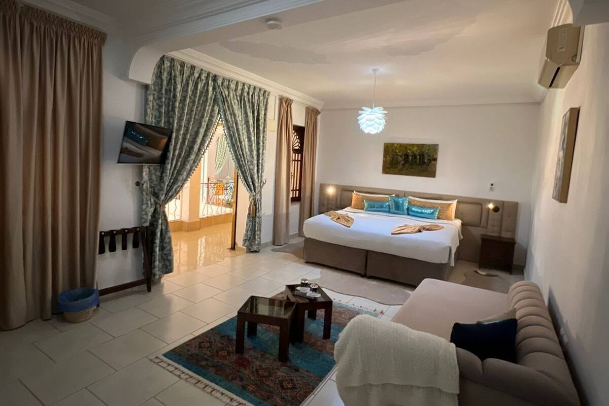 Uma sala de estar ampla com uma cama grande, um sofá, uma mesa de centro e uma televisão.