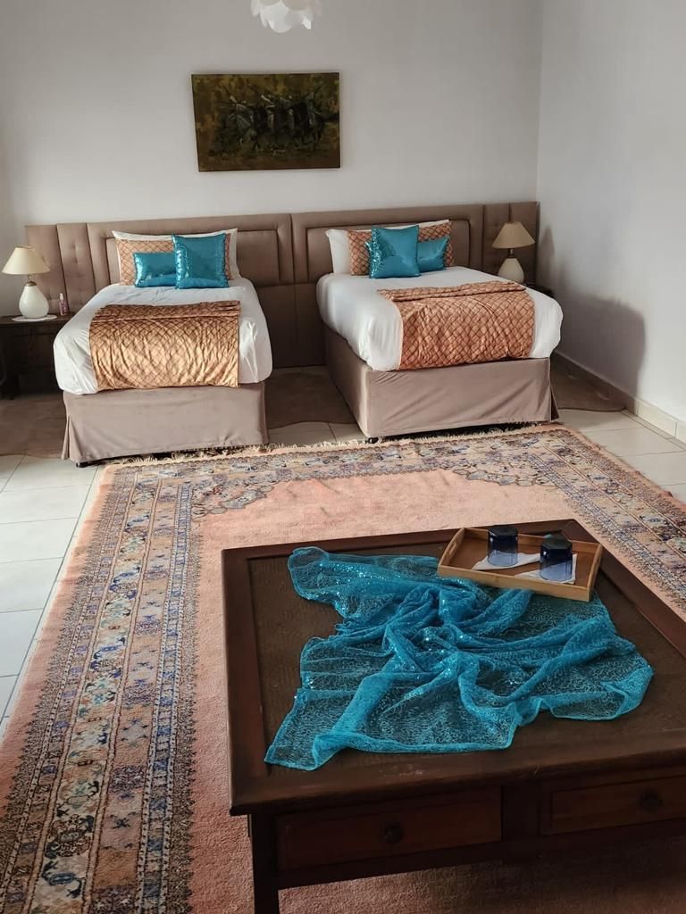 Una habitación de hotel con dos camas, una mesita de centro y una alfombra estampada.