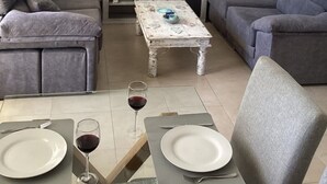 Una sala de estar con dos sofás grises, una mesa de centro con estampado floral, un televisor de pantalla plana sobre un mueble bajo, y un cuadro de un árbol rosado en la pared.