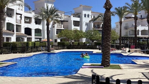 Zona de piscina con palmeras y un paseo vallado.