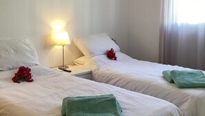 Habitación de hotel con dos camas individuales, una lámpara de noche y una ventana con cortinas.
