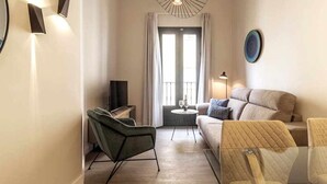 Una sala de estar moderna con un sofá, sillas, un televisor y una mesa de vidrio.