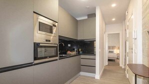 Una cocina moderna con electrodomésticos integrados, encimera oscura y suelo de madera.