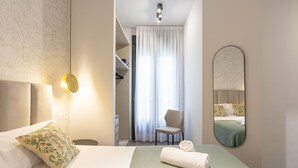 Een hotelkamer met een bed, een stoel, een spiegel en een kast.