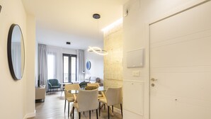 Een moderne woonkamer met een eethoek, een grote spiegel en een witte deur.