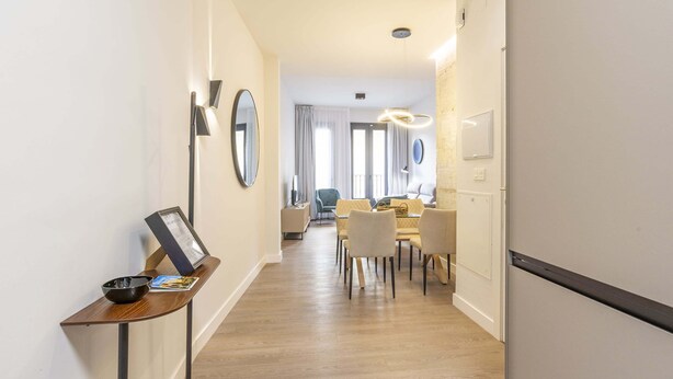 Een hotelgang met een eetgedeelte, een spiegel en een tafel met een kom en een menukaart.