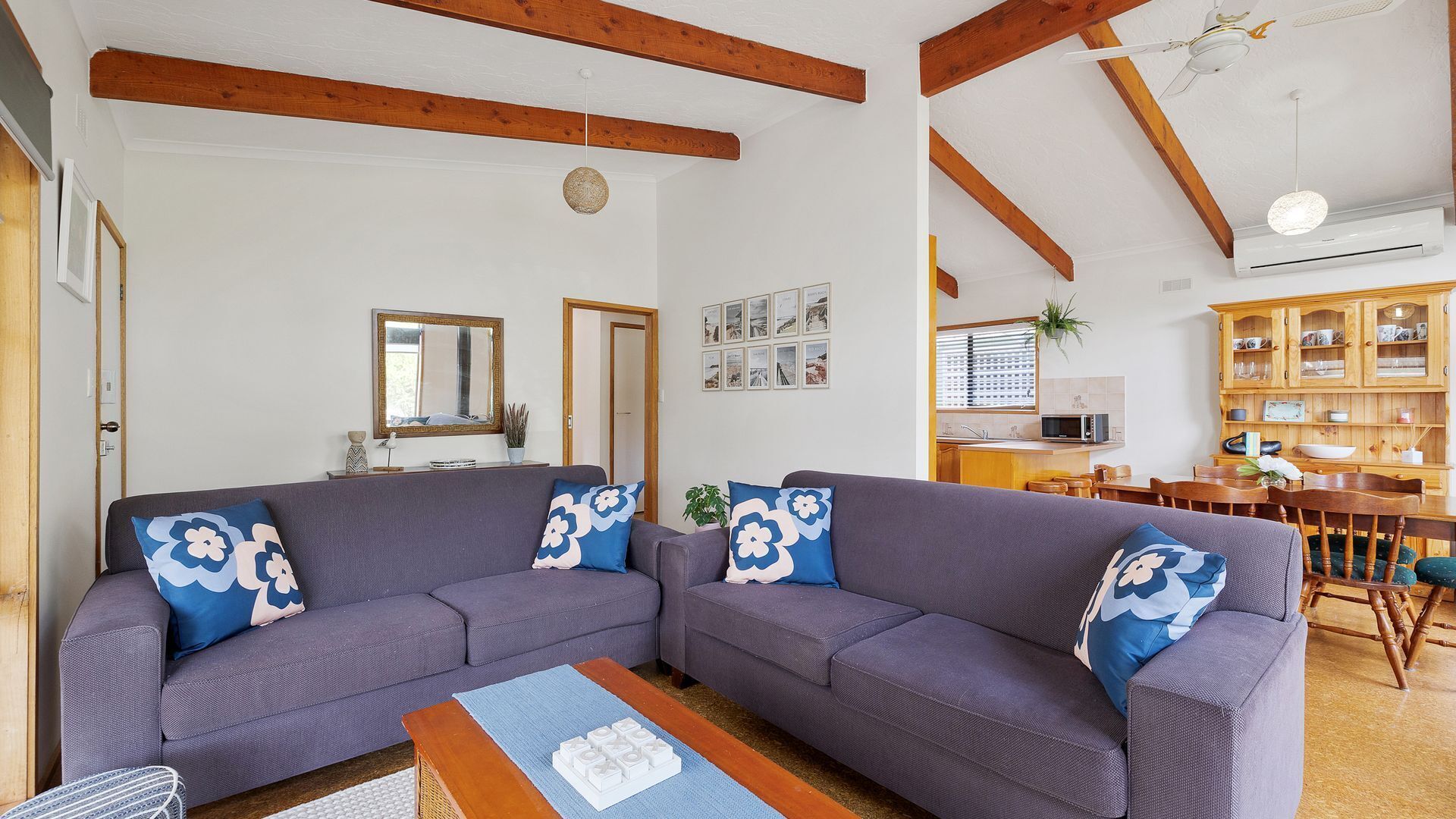 A living room with two sofas, a coffee table, and a dining area with wooden chairs and a table.