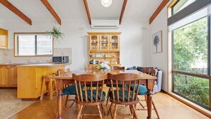 Een keuken met houten kasten, een magnetron, en een eethoek met een houten tafel en stoelen.