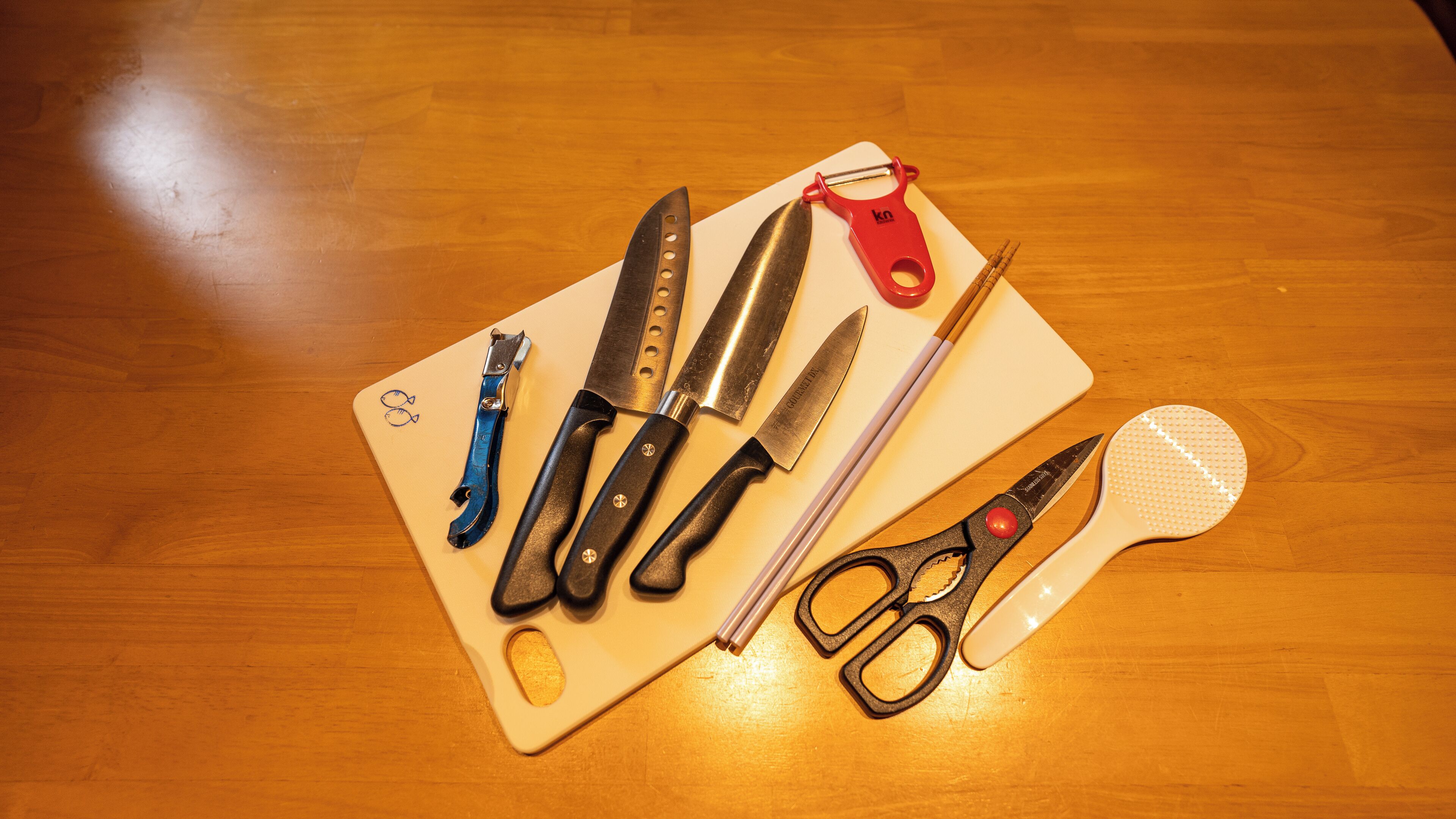 Ein Holztisch mit verschiedenen Küchenutensilien, darunter Messer, eine Schere und eine Reibe.