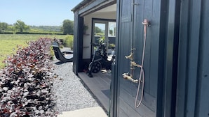 A modern building with a grey exterior, a covered outdoor area with a stationary bike, and a hose attached to the wall. - Ashlea (Launceston)