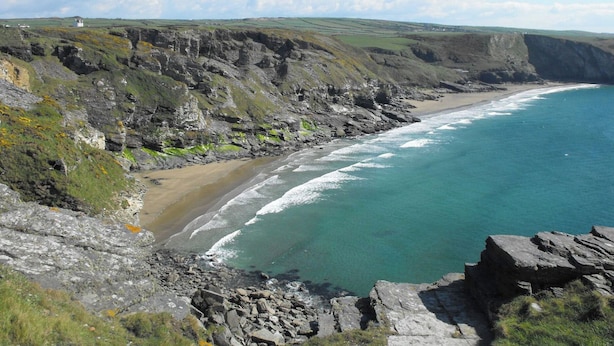 A coastal landscape with rocky cliffs, a sandy beach, and a clear blue sea. - Ashlea (Launceston)