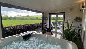 A hot tub with a view of a green field, a spinning exercise bike, and a door leading outside. - Ashlea (Launceston)