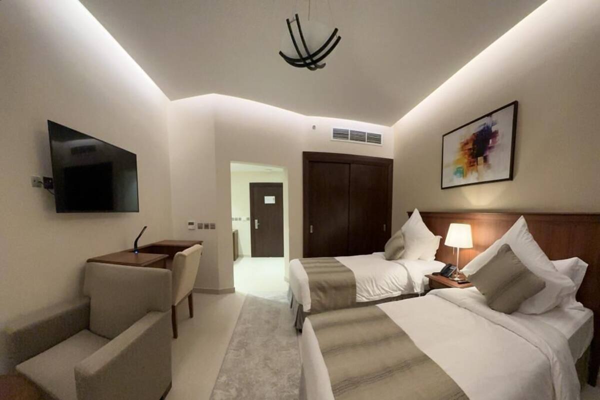 A hotel room with two beds, a TV, a desk, and a chair.