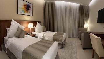 A hotel room with two beds, a desk, a chair, a TV, and a large window with curtains.