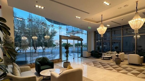 Um hall amplo com uma grande parede de vidro, mobiliário moderno e luminárias elegantes.
