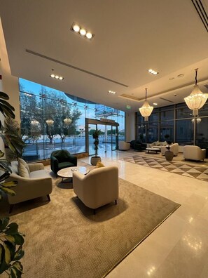 A spacious lobby with a large glass wall, modern furniture, and elegant lighting fixtures. - Hotel ALdoliaa (Unaizah)