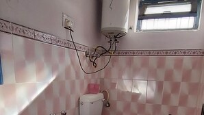 Un baño con un lavabo blanco, un inodoro y un cubo rojo.