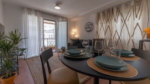 A dining area with a round table set for four, chairs, and a potted plant. - Amazinn Places - Cabañal Boutique (Valencia)