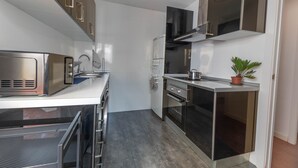 A modern kitchen with stainless steel appliances, a built-in oven, and a potted plant. - Amazinn Places - Cabañal Boutique (Valencia)