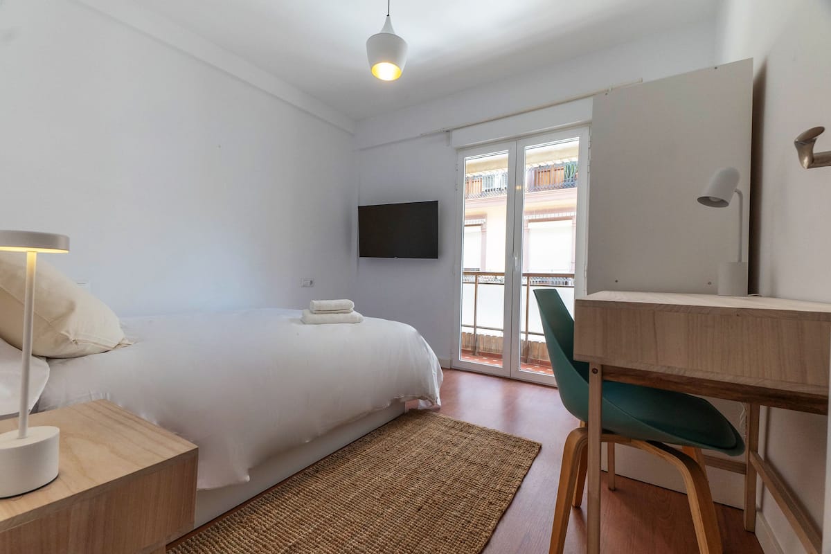 Ein Hotelzimmer mit Bett, Schreibtisch, Stuhl, Fernseher und einem Balkon mit Aussicht.