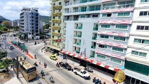 Un hotel de varios pisos con balcones, un patio central y vistas del área urbana circundante.