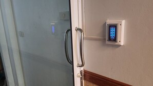 Una puerta con picaporte metálico y un teclado de cierre en la pared de al lado.