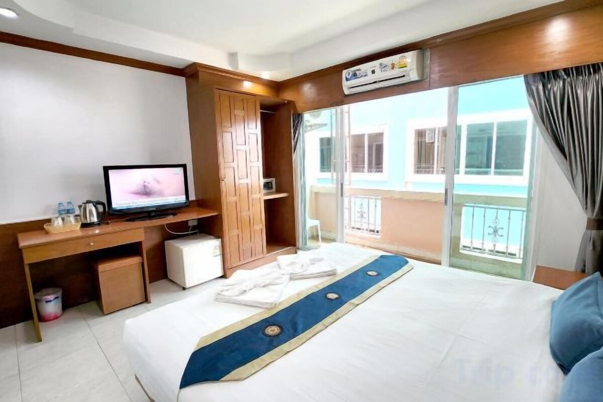 Een hotelkamer met een bed, een televisie, een bureau en een balkon met uitzicht.
