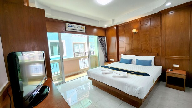 Habitación de hotel con cama, televisión, mesita de noche y vistas al balcón exterior.