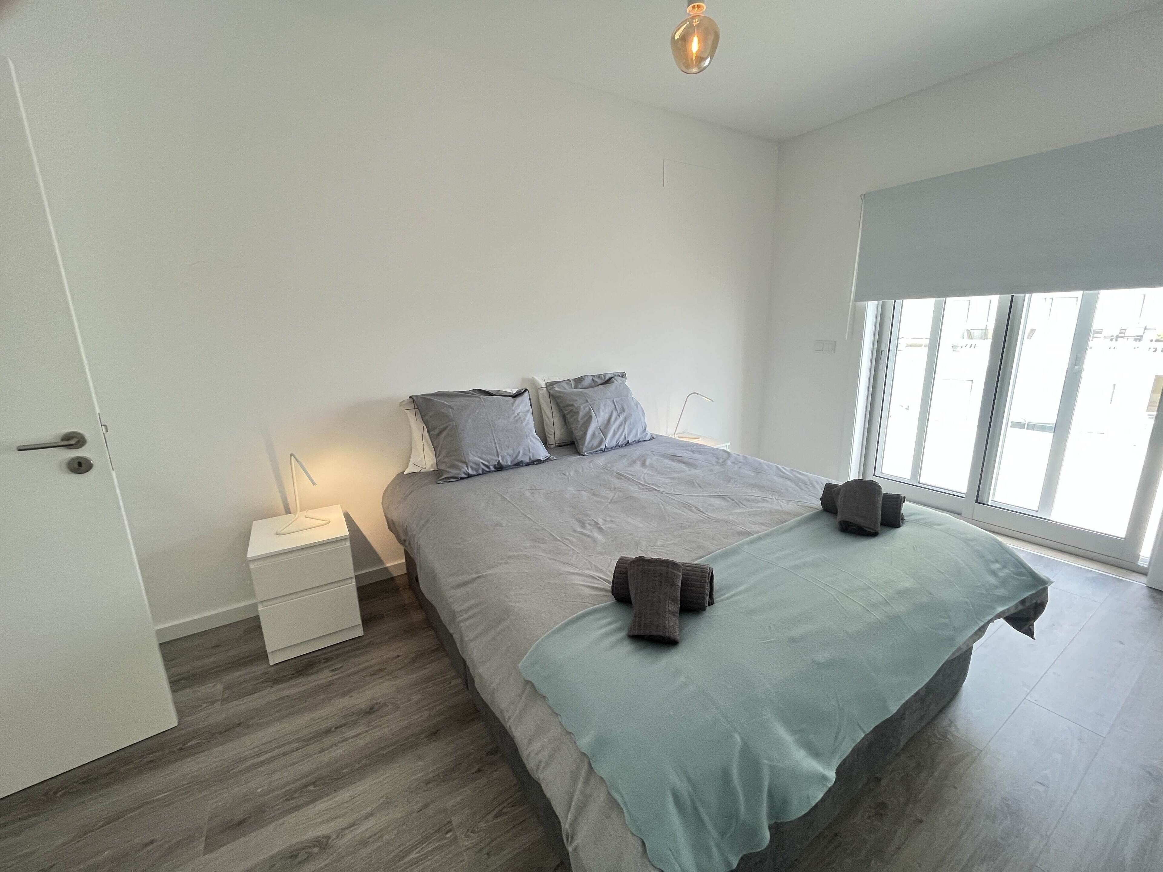 Un dormitorio moderno con una cama grande, una mesita de noche y una ventana con vistas.