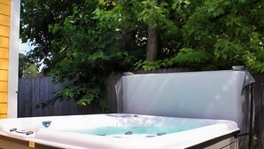 A hot tub in an outdoor setting with a wooden fence and trees in the background. - Downtown New Buffalo 3BR | 8-Person Hot Tub, Fire Pit, 1 Mi to the Beach (New Buffalo)