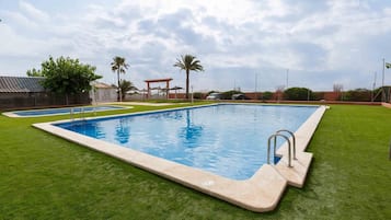 Relax by the pool surrounded by lush greenery and a shaded gazebo.