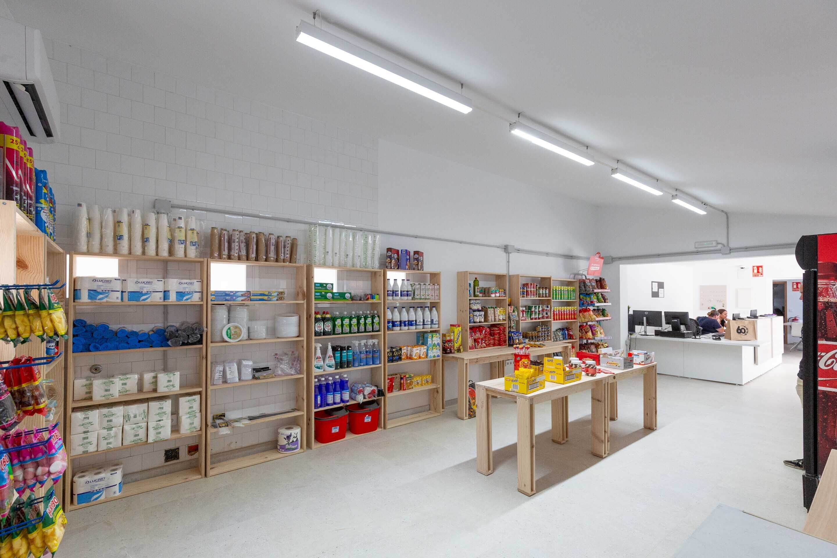 A well-organized store with shelves stocked with various products, a central display table, and a reception area in the background.
