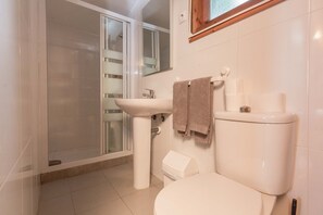 A bathroom with a toilet, sink, and shower.