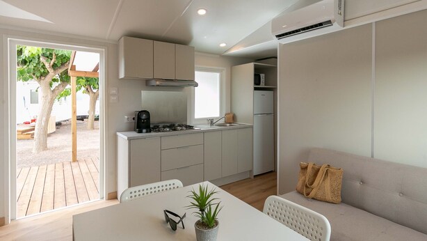 Una cocina compacta con zona de comedor, un sofá y una planta en maceta.