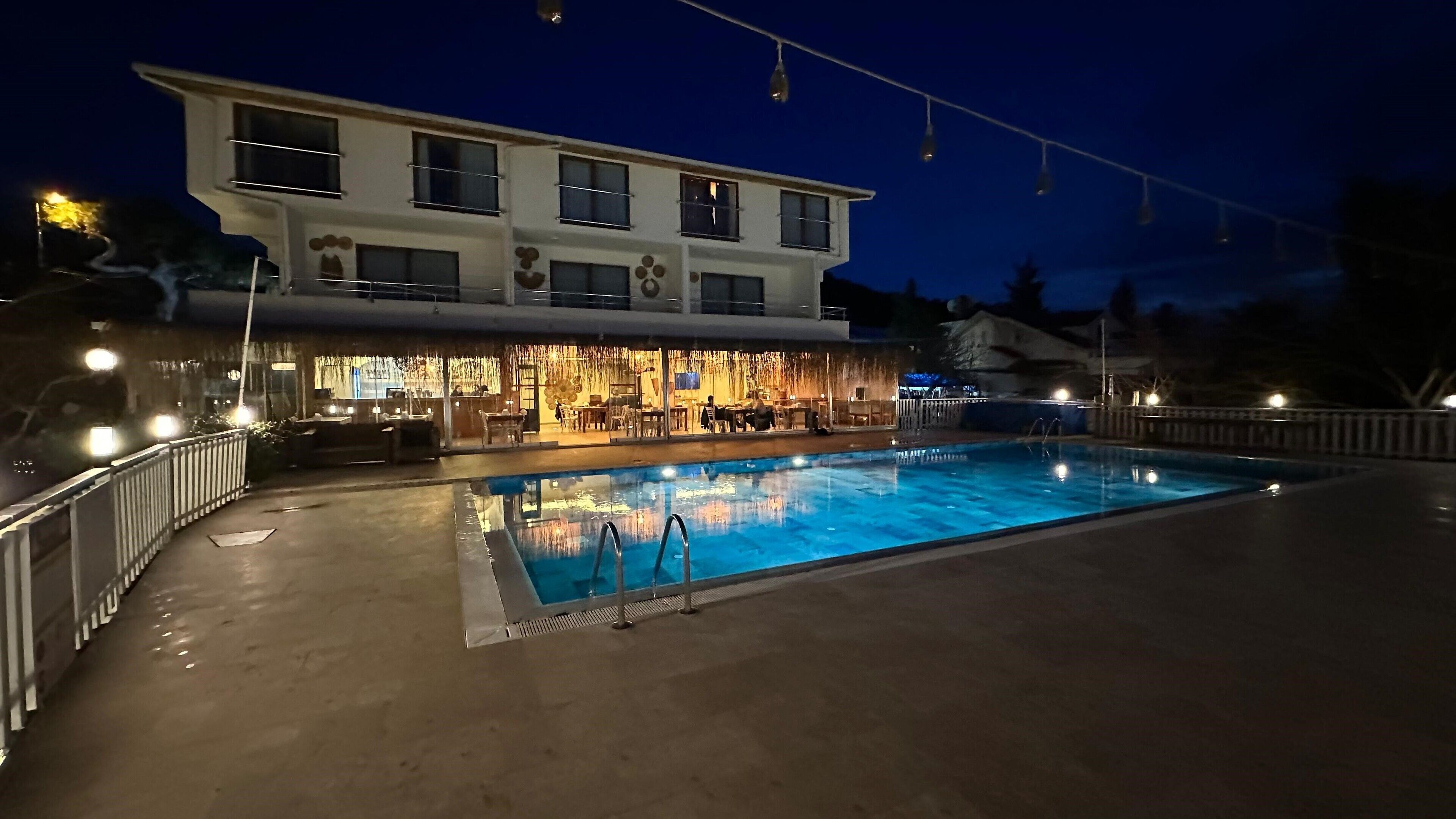 A swimming pool with a bar and seating area adjacent to a building with multiple windows and a balcony.