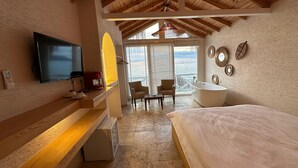 A bedroom with a large bed, a TV, a coffee maker, and a view of the sea through the window. - The Roof ADA (Adalar)