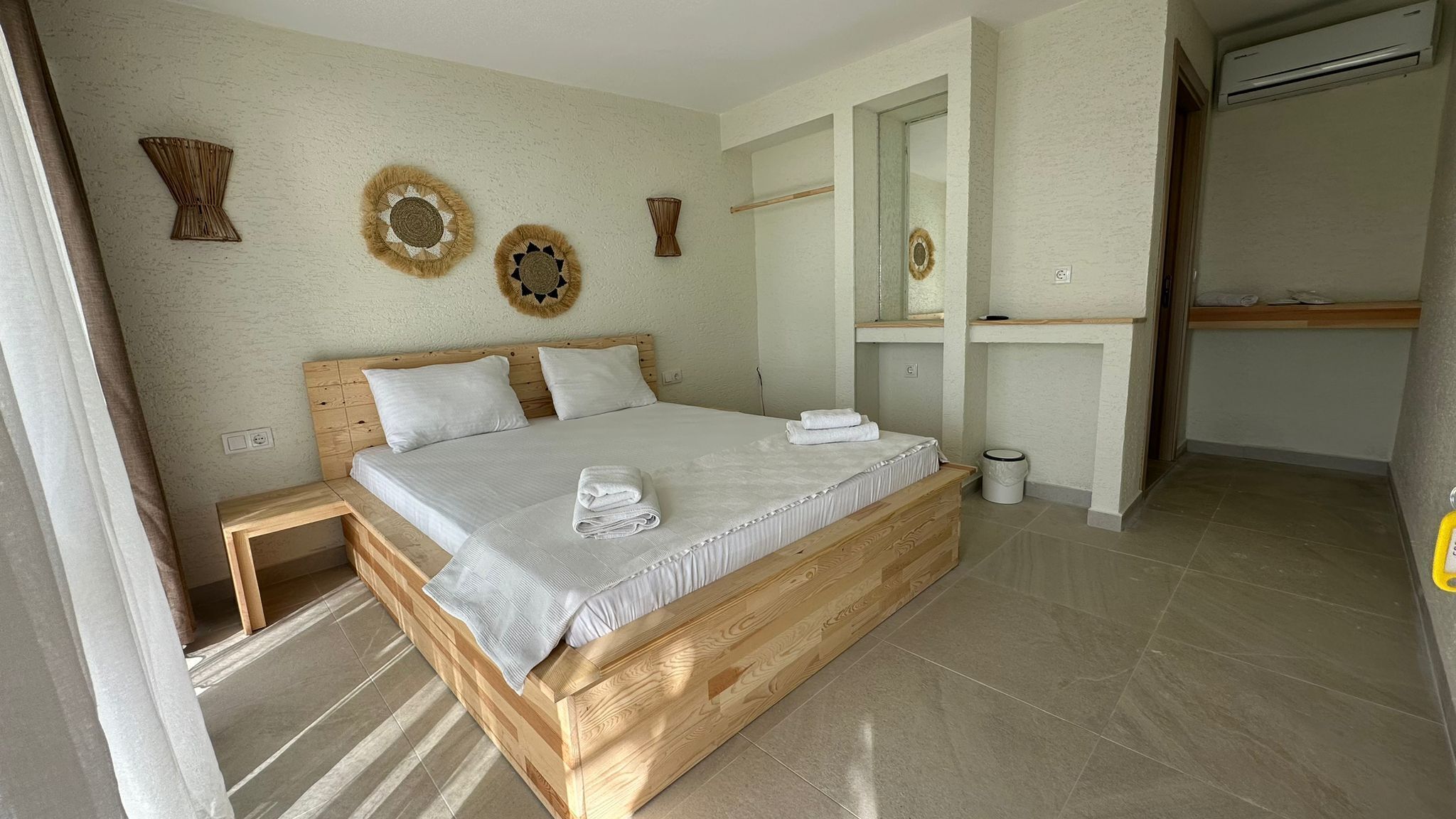 Un dormitorio con cama de madera, ropa de cama blanca y decoración en la pared.
