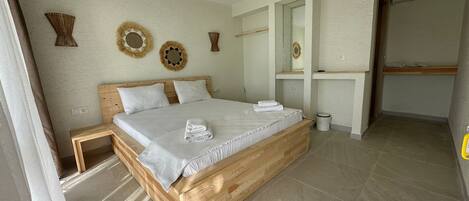 Un dormitorio con cama de madera, ropa de cama blanca y decoración en la pared.