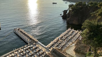 Ein Hotel an der Küste mit einer Terrasse mit Blick auf das Meer, ausgestattet mit Liegestühlen und Sonnenschirmen.