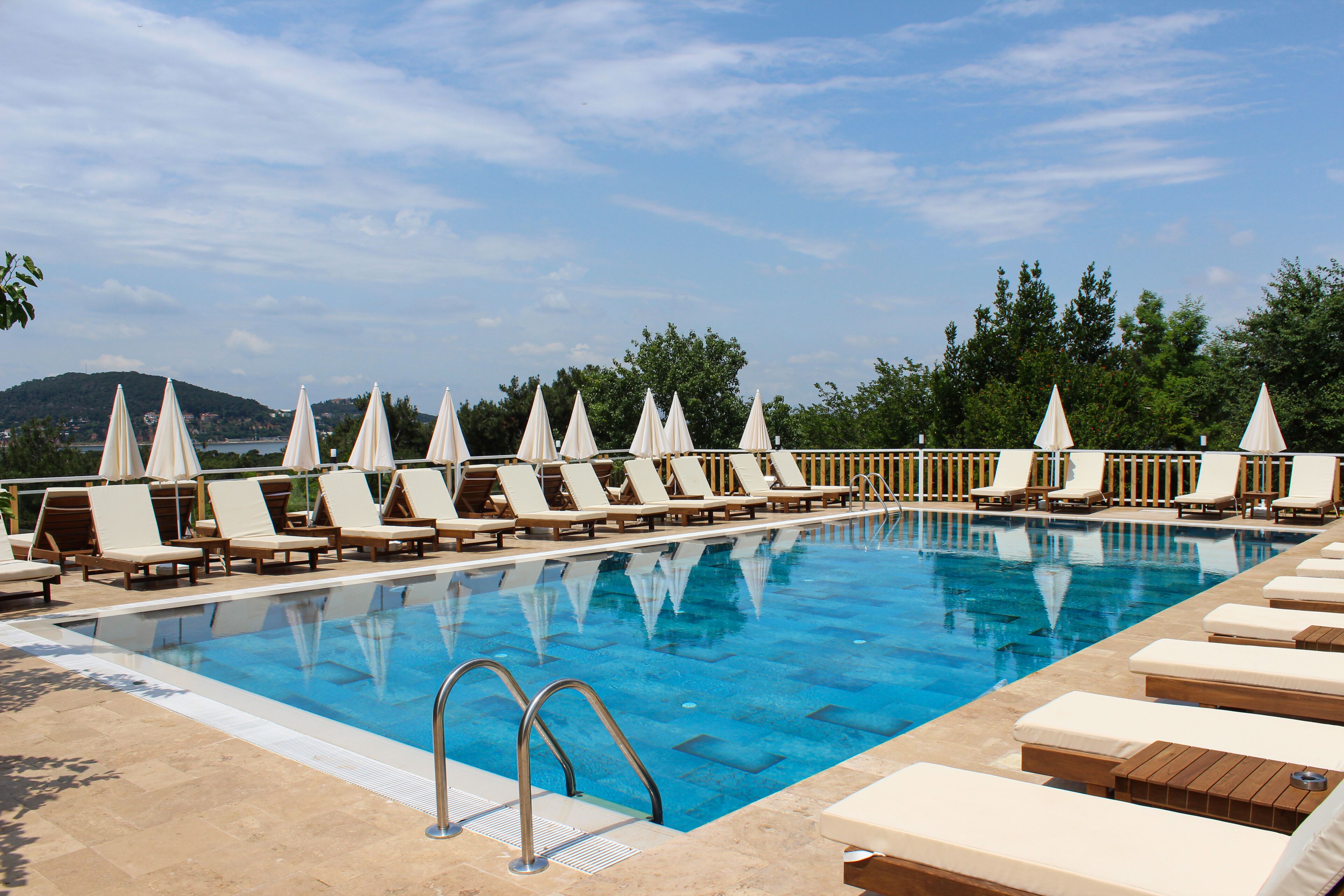 Una piscina con sillas de descanso y sombrillas dispuestas a lo largo de la orilla.