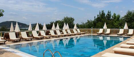 Una piscina con sillas de descanso y sombrillas dispuestas a lo largo de la orilla.