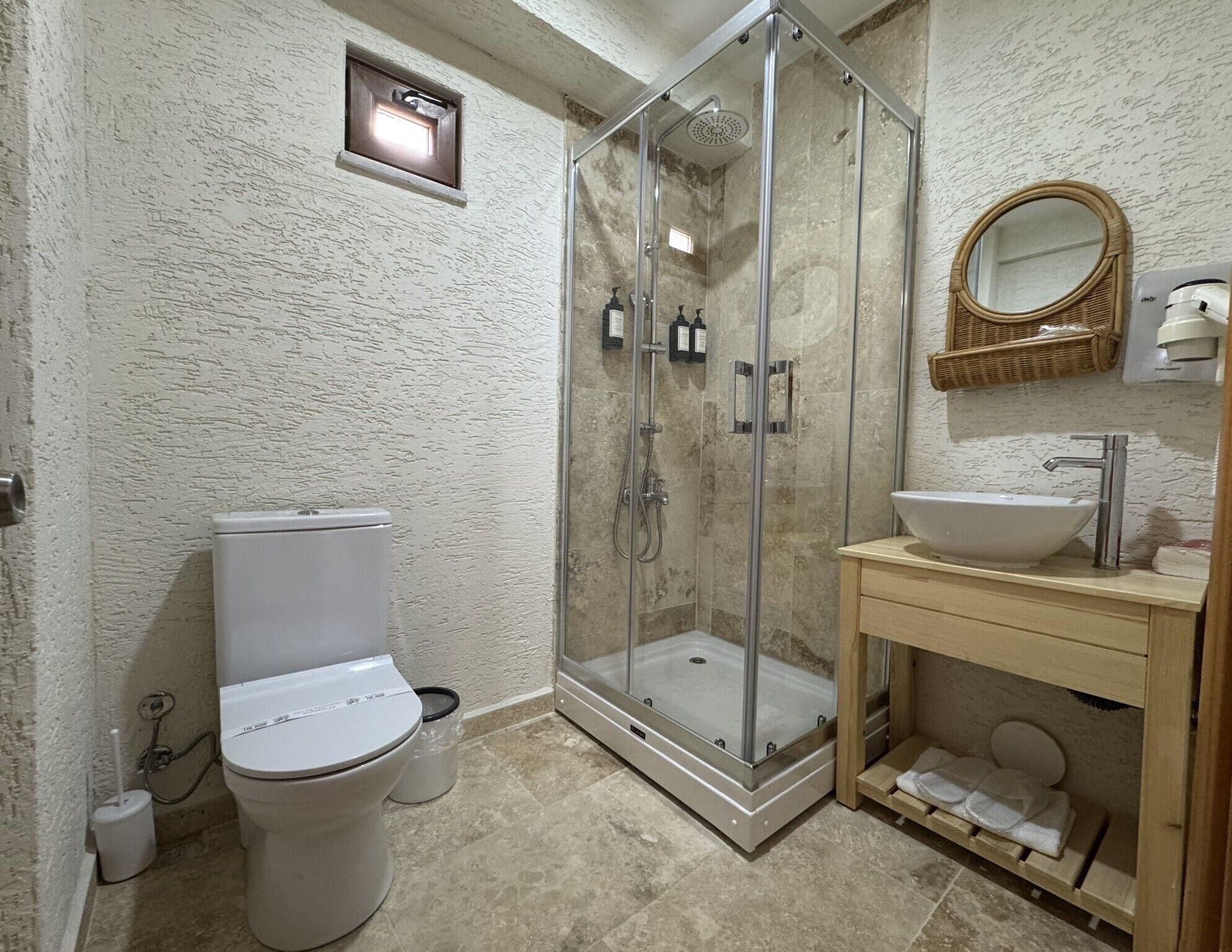 A bathroom with a glass-enclosed shower, a toilet, a sink, and a mirror.