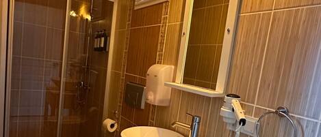 A bathroom with a wooden vanity, a sink, a toilet, and a shower area.