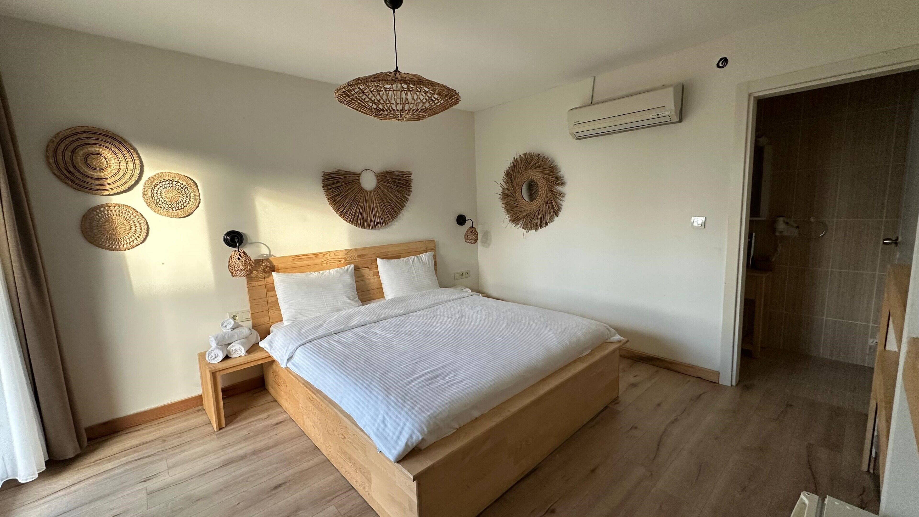 A bedroom with a wooden bed, white bedding, and woven wall decorations.