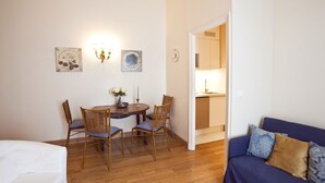 A room with a wooden dining table, two chairs, a blue sofa, and a white bed. - Two Bedrooms Flat Close Place Vendome (Paris)