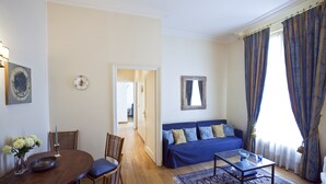 A living room with a sofa, coffee table, and dining table. There is a hallway leading to another room. - Two Bedrooms Flat Close Place Vendome (Paris)